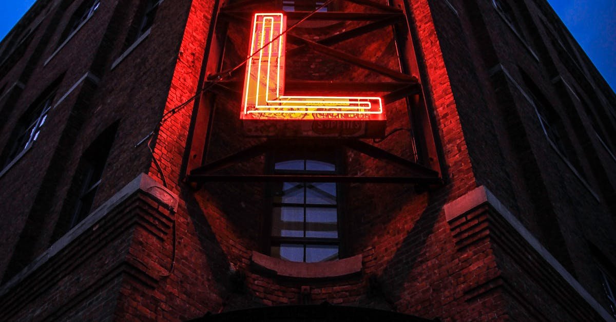 Eye-catching low angle shot of a neon hotel sign illuminating a brick building facade at dusk.
