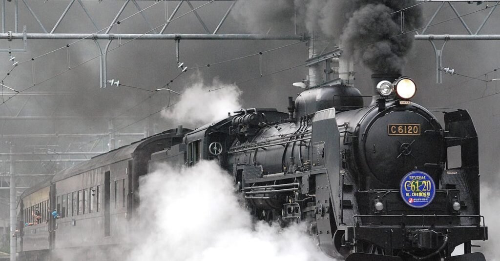 Steam locomotive releasing smoke and steam on a rail track, showcasing vintage train transportation.