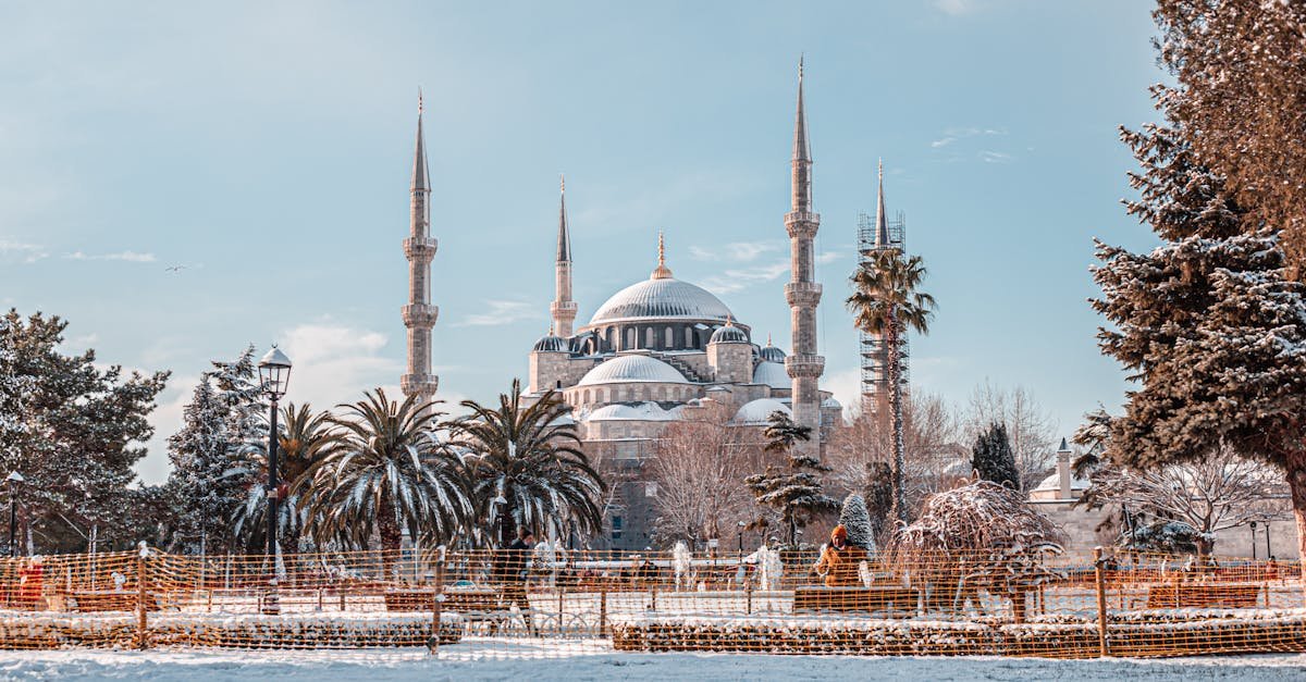 A captivating winter scene of the Sultan Ahmed Mosque in Istanbul, Turkey, with snow-covered ground and clear blue sky.