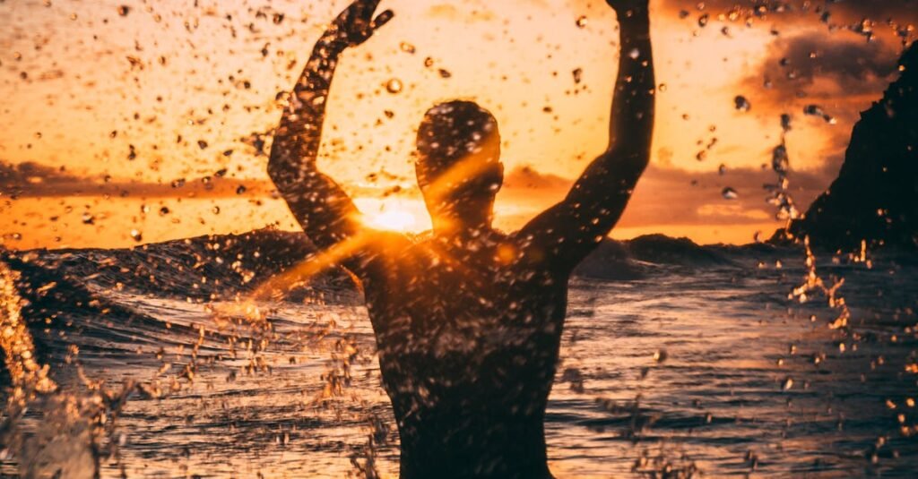 Silhouette of a person enjoying the ocean at sunset, creating a dynamic seascape scene.