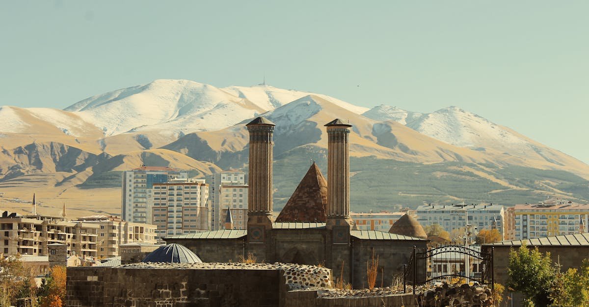 The historic Cifte Minareli Medrese with snow-covered mountains in Erzurum, Turkey.