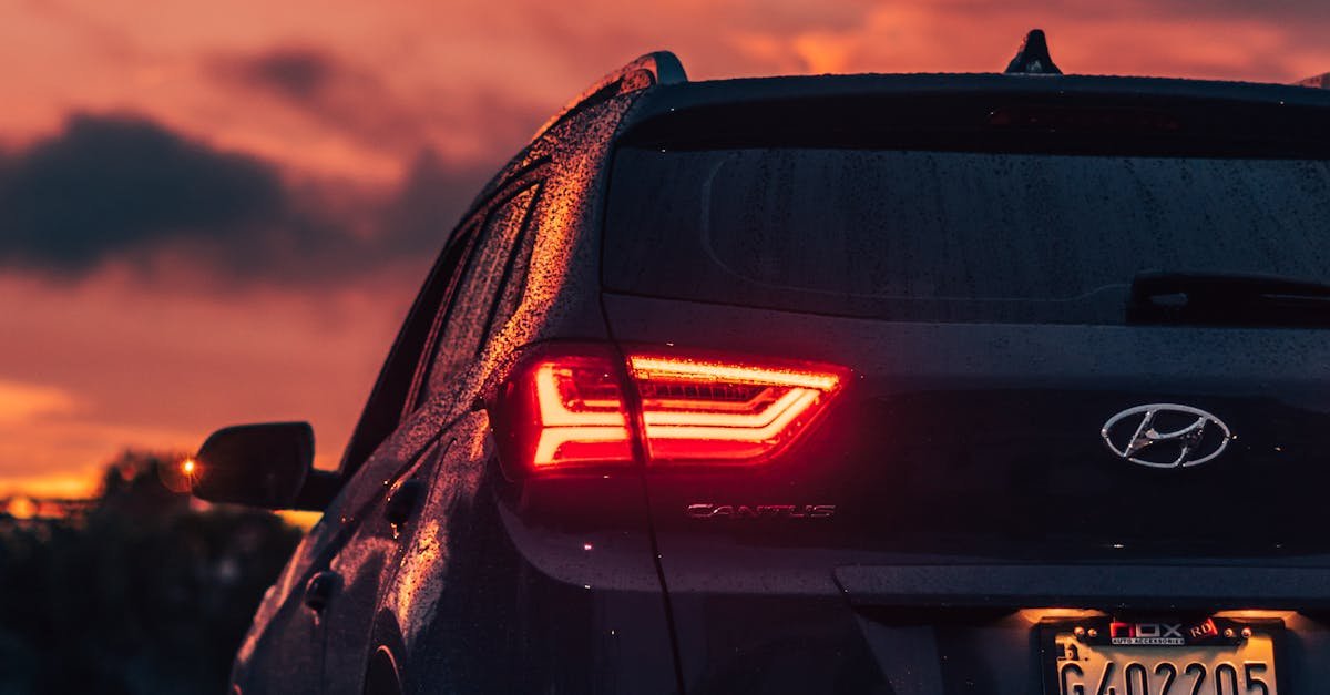 Rear view of a modern Hyundai SUV on a wet road during a vibrant sunset, showcasing dramatic cloudscape.