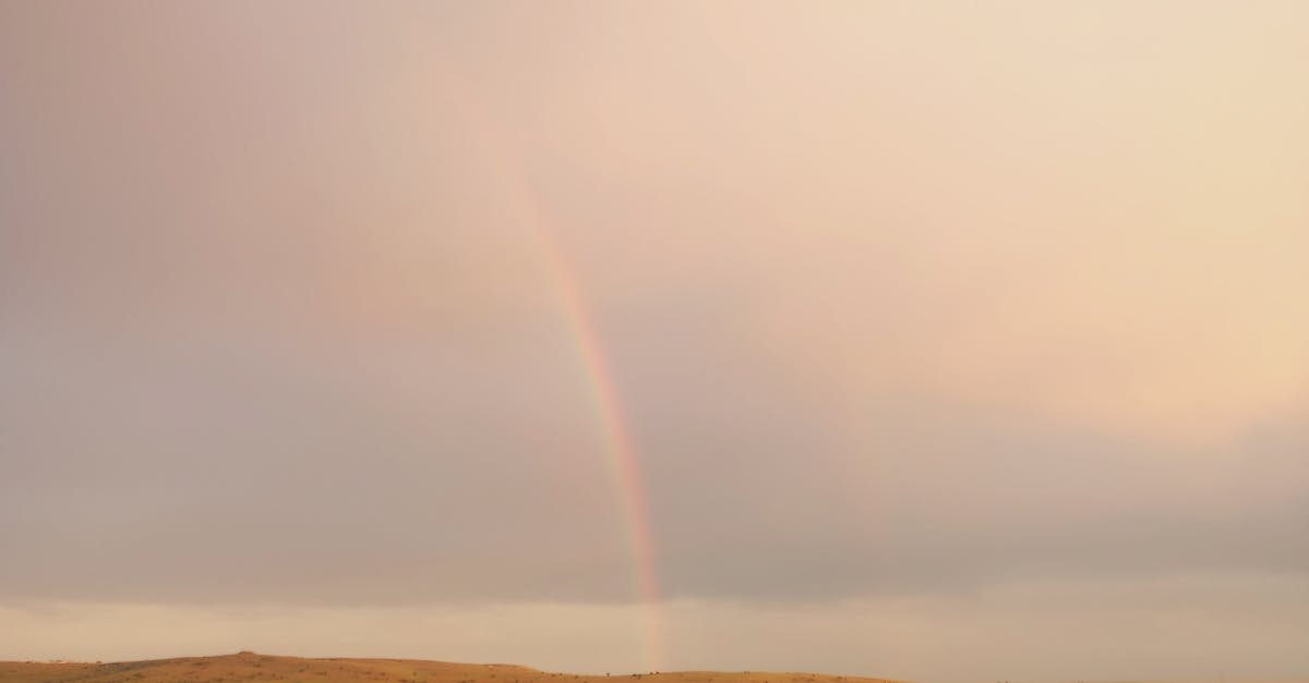 A serene aerial capture of rural Gaziantep, Türkiye with a rainbow over green fields and buildings.
