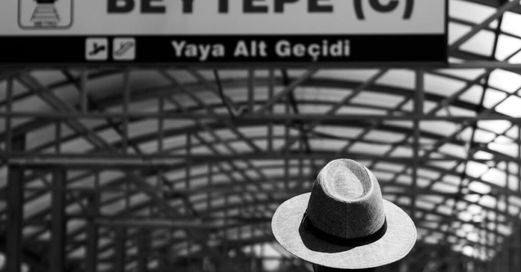 A black and white image of a man in a hat standing at Beytepe Metro Station in Ankara, Türkiye.