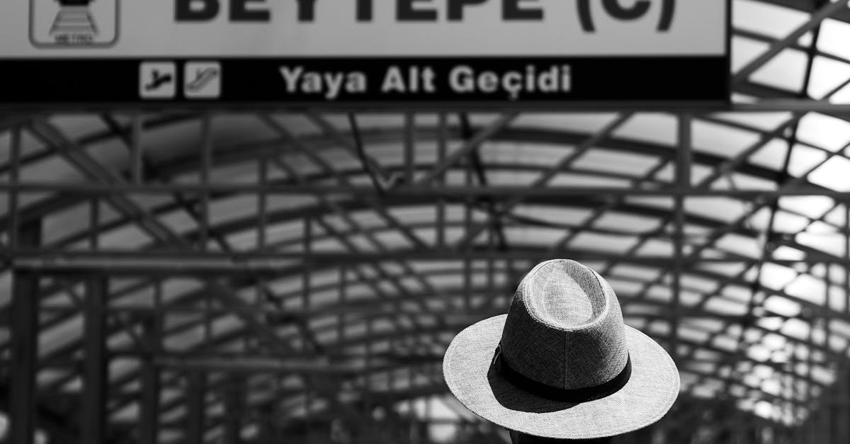A black and white image of a man in a hat standing at Beytepe Metro Station in Ankara, Türkiye.