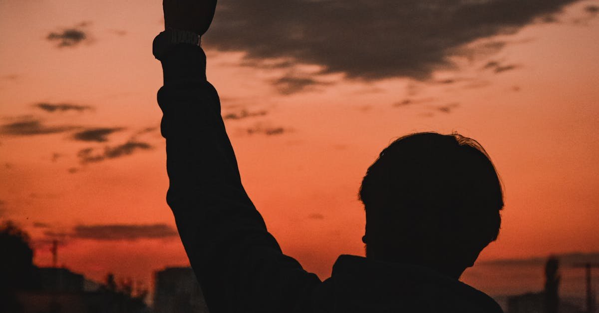 A silhouette of a person waving during a vibrant sunset in Elbistan, Türkiye.