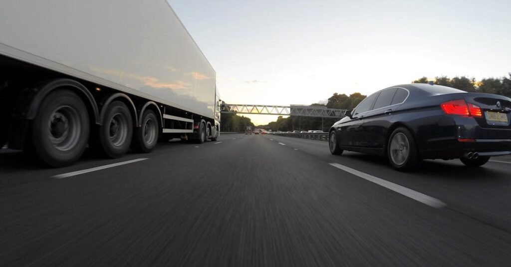 Cars and a truck speed along a highway under the clear sky, showcasing transportation dynamics.
