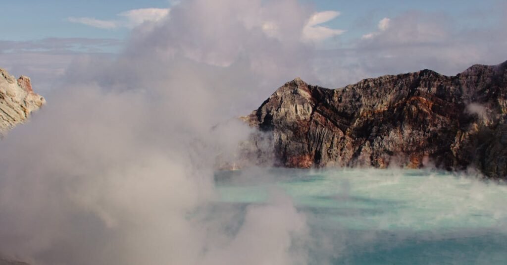 A breathtaking view of the steaming Kawah Ijen crater lake in Indonesia, surrounded by rugged cliffs.