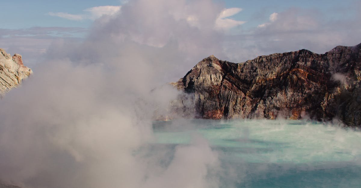 A breathtaking view of the steaming Kawah Ijen crater lake in Indonesia, surrounded by rugged cliffs.