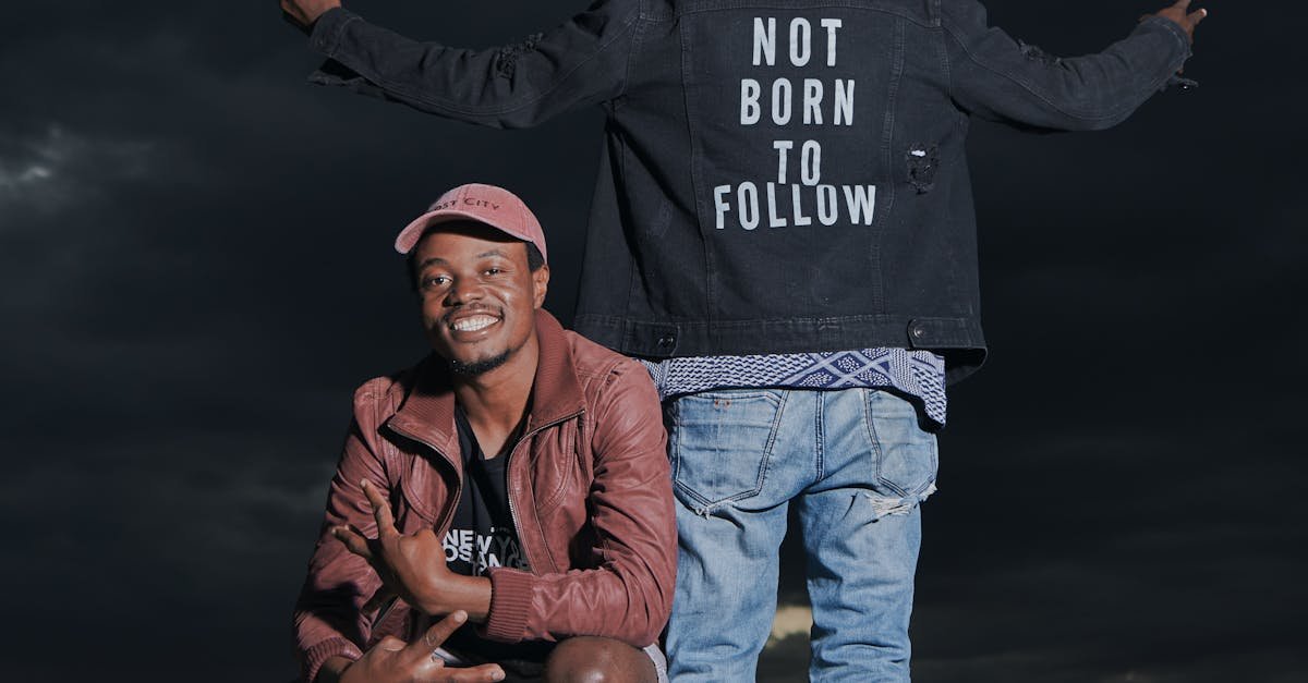 Two stylish young men pose with a bold statement jacket against a dramatic night sky.