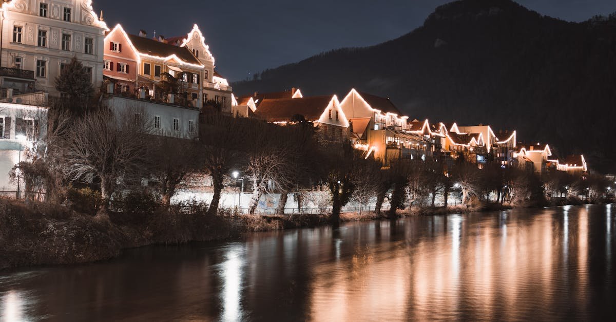 Illuminated houses along the river in Frohnleiten, Austria, creating a serene night scene.