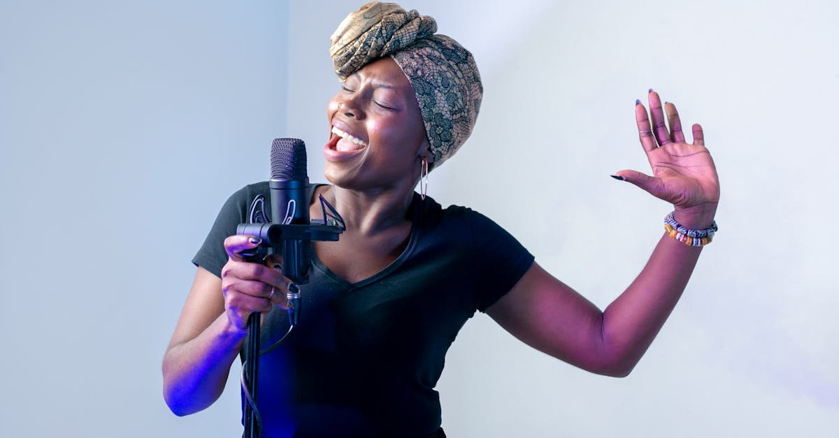 Passionate African woman singing in a music studio with a microphone and headscarf.