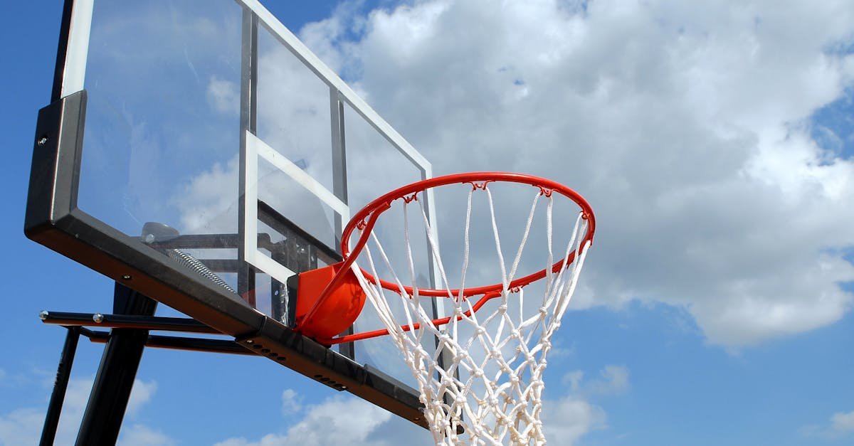A basketball hoop and backboard set against a clear blue sky, capturing the essence of outdoor sports.
