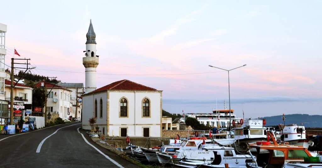 Charming scene of Kilitbahir harbor showcasing a historic mosque and boats at sunset in Çanakkale, Türkiye.