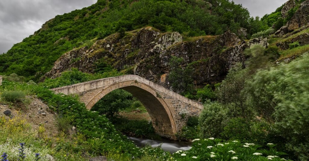 A picturesque historic stone bridge surrounded by lush greenery in Gümüşhane, Türkiye.