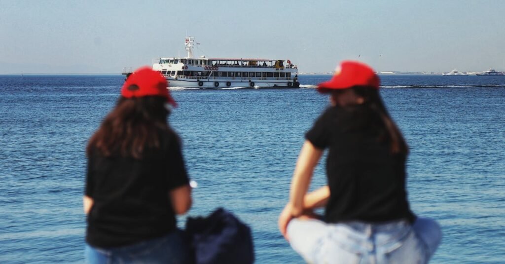 Two women relaxing by the Aegean Sea in Izmir, watching a ferry pass on a sunny day.