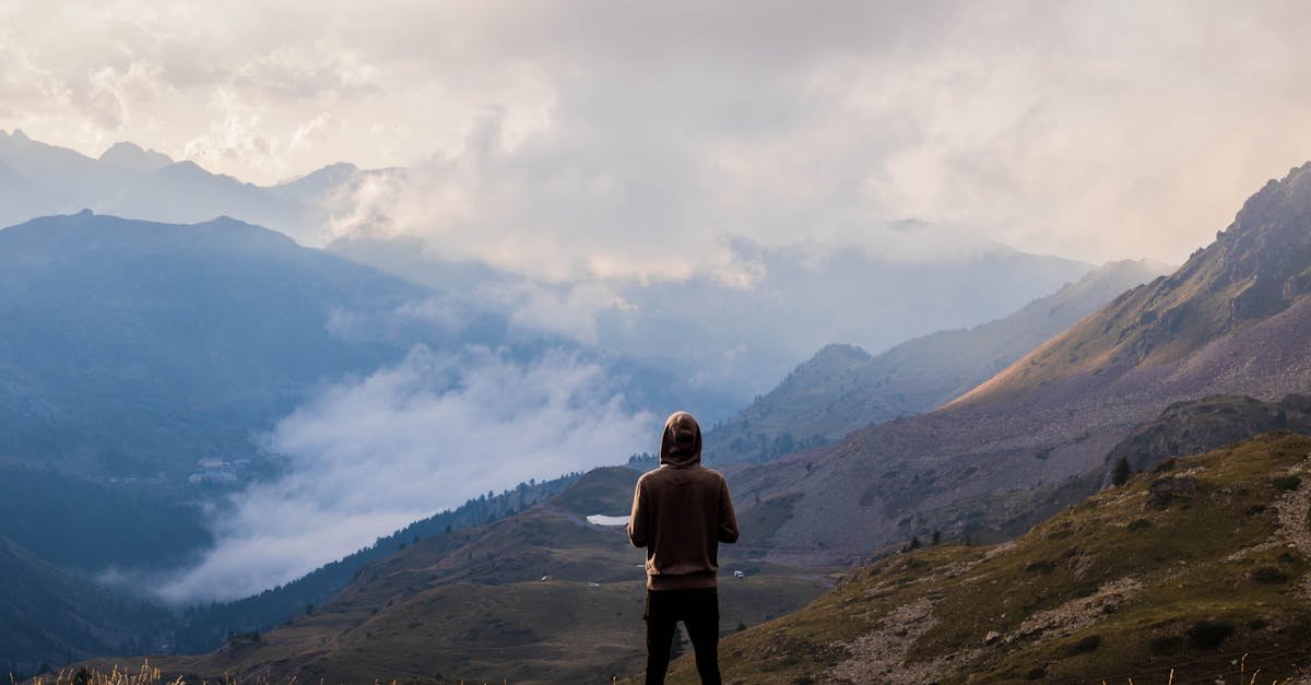 A lone hiker stands in awe of the misty mountain landscape in France.