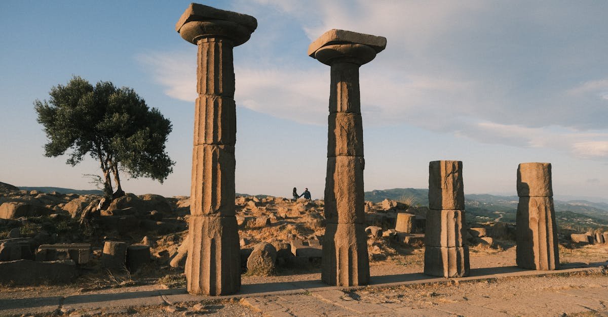 Explore the ancient ruins of Behramkale, Türkiye, under a warm sunset sky, capturing historical columns and landscape.