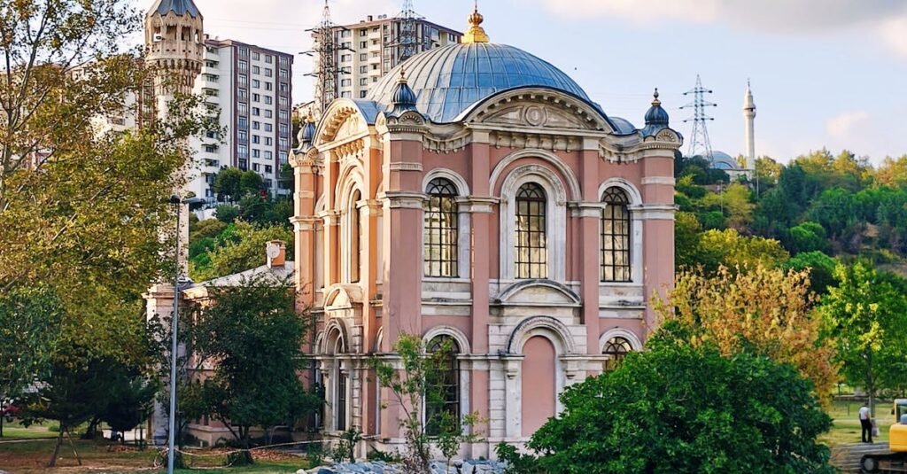 Picturesque view of a historic mosque by the river in İstanbul, Türkiye, with clear reflections and lush surroundings.