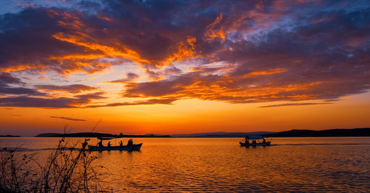 Gorgeous sunset over a peaceful lake in Bursa, Türkiye with boats silhouetted against vibrant skies