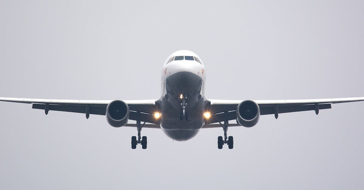 A commercial airliner captured head-on, preparing to land against a cloudy sky.