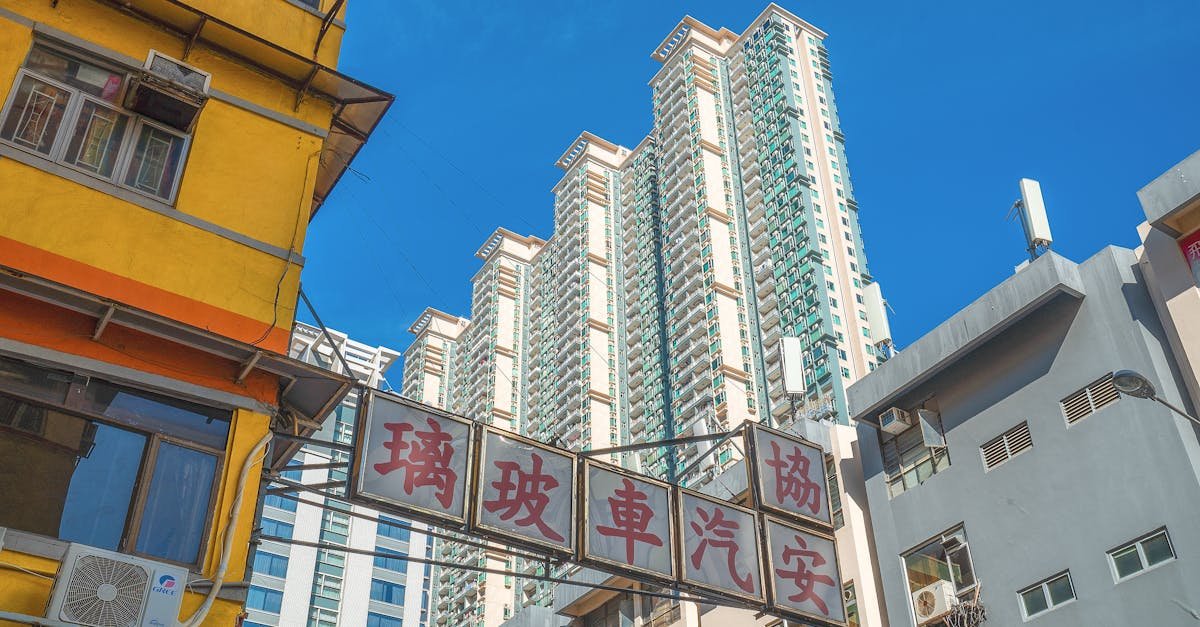 Low angle view of vibrant high-rise buildings in downtown Hong Kong under a clear blue sky.