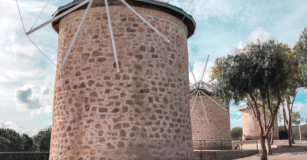 Scenic view of traditional stone windmills in Çeşme, Turkey under a bright sky.
