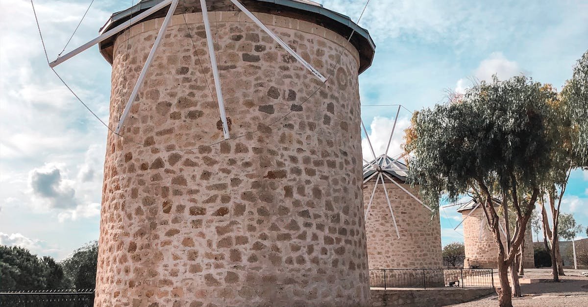Scenic view of traditional stone windmills in Çeşme, Turkey under a bright sky.