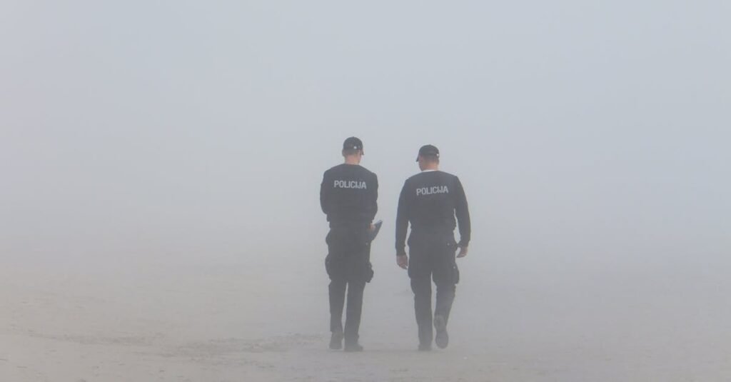 Two policemen walking on a foggy beach, creating an atmospheric scene.