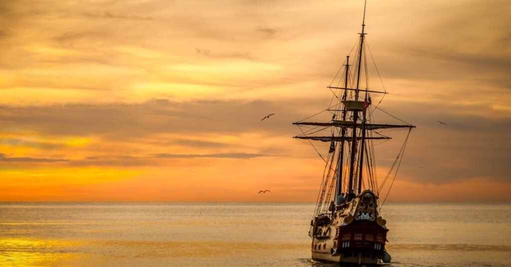 A majestic pirate ship sails into the serene waters at sunset, casting a dramatic silhouette.