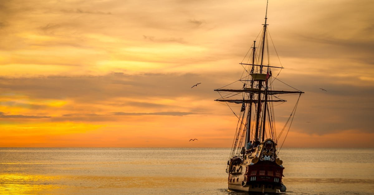A majestic pirate ship sails into the serene waters at sunset, casting a dramatic silhouette.