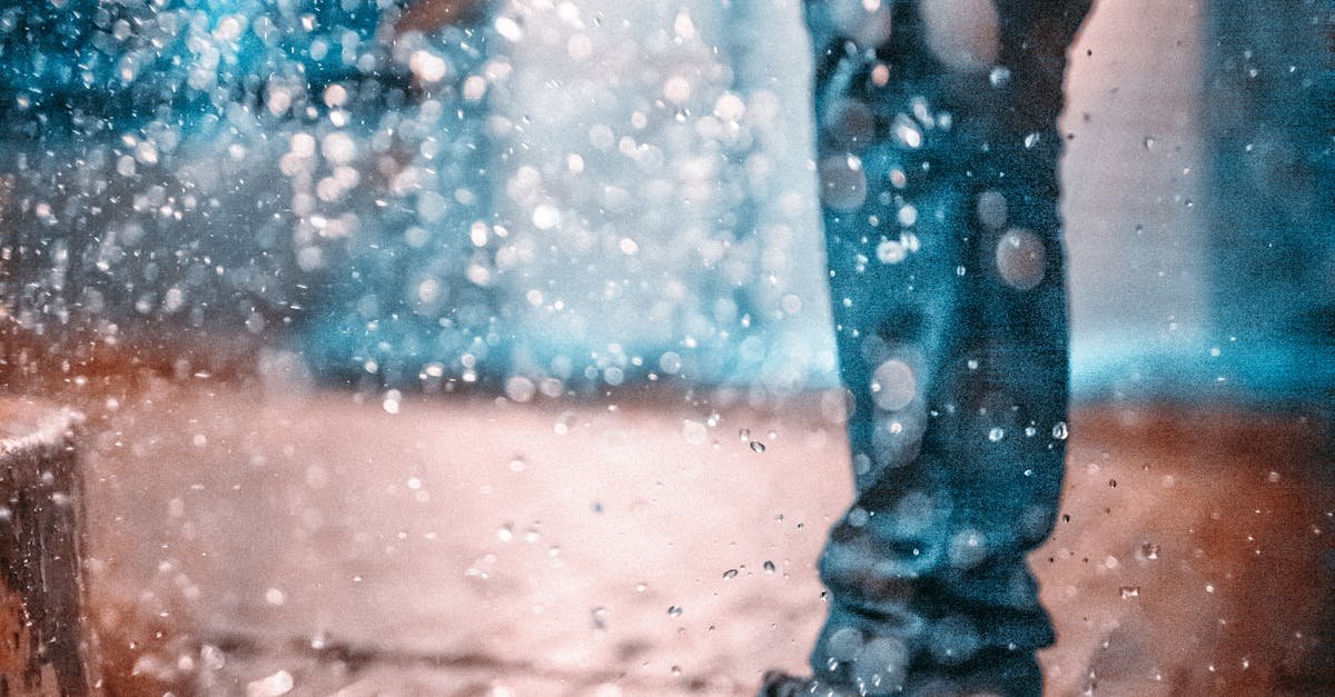 A stylish individual walks through a rainy urban street, creating dynamic water splashes.