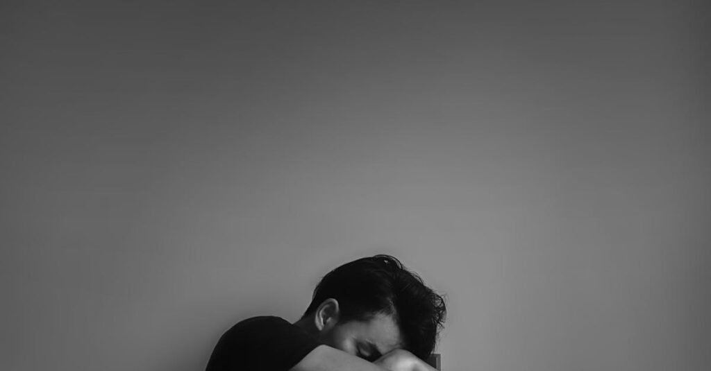 A black and white portrait of a man sitting alone, evoking emotion and contemplation.