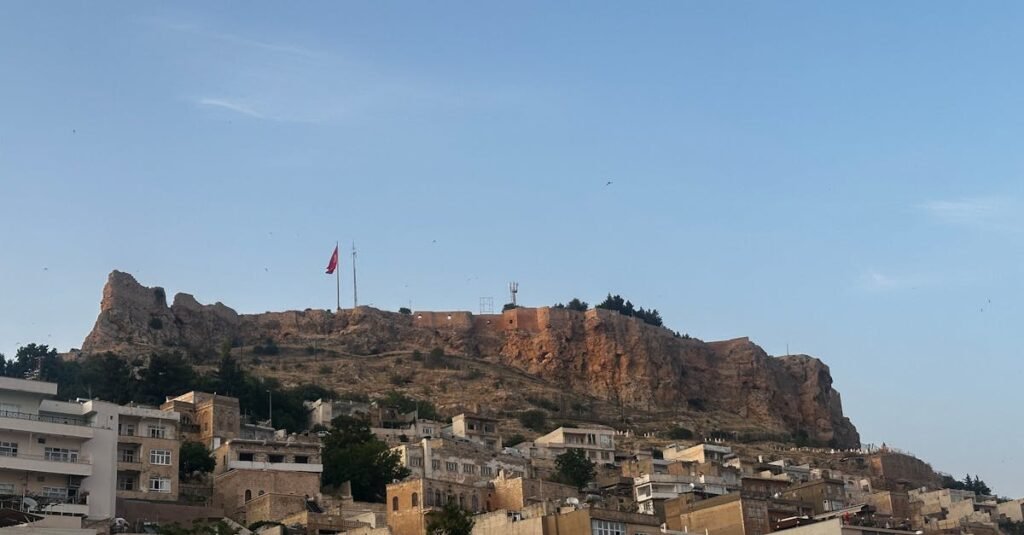 Scenic view of Mardin's ancient city and castle under clear blue sky.