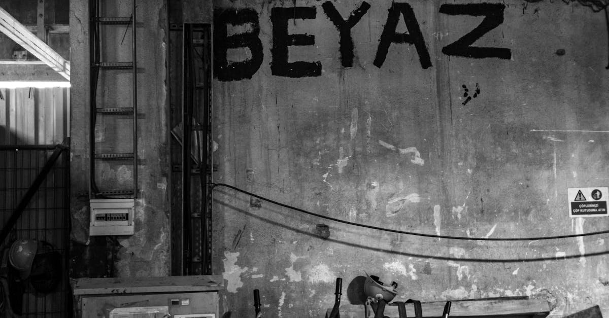 Monochrome photo of an industrial warehouse interior with graffiti art and scattered tools.