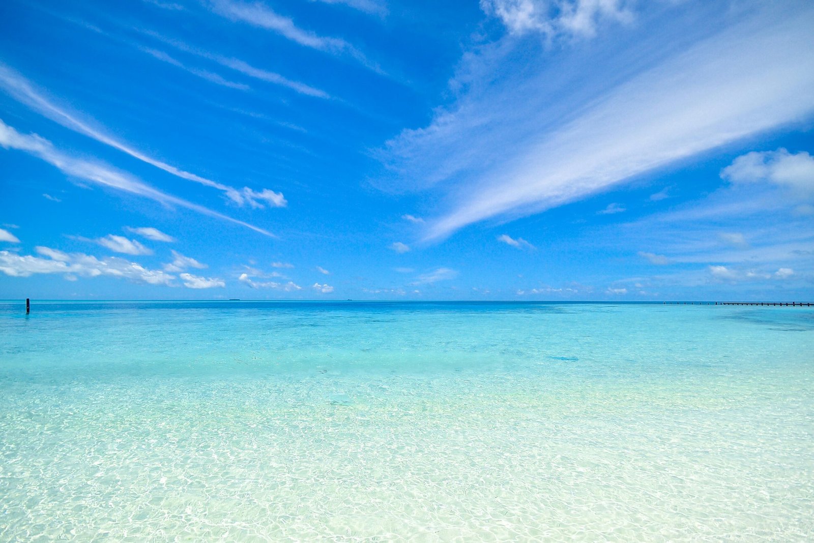 Experience the tranquil turquoise waters and clear sky at Laamu Atoll, Maldives. Perfect for a relaxing getaway.