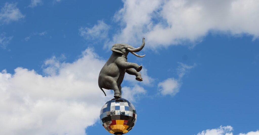 Statue of an elephant balancing on a disco ball in Niagara Falls against a blue sky.