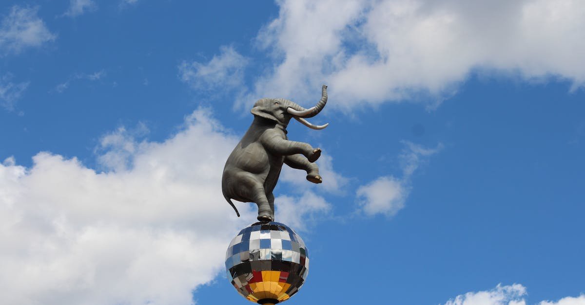 Statue of an elephant balancing on a disco ball in Niagara Falls against a blue sky.