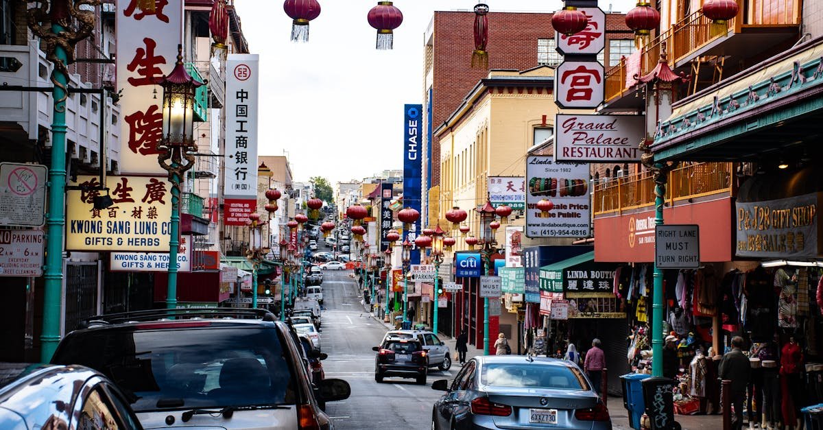 Bustling Chinatown street with hanging lanterns, shops, and vehicles.