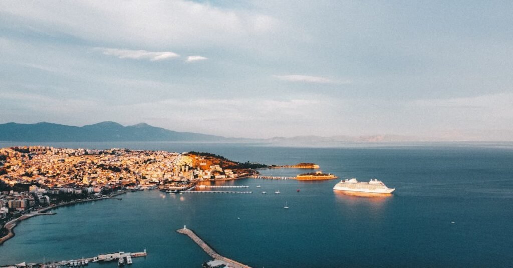 Aerial view of Kusadasi harbor with yachts and a cruise ship under a bright sky.