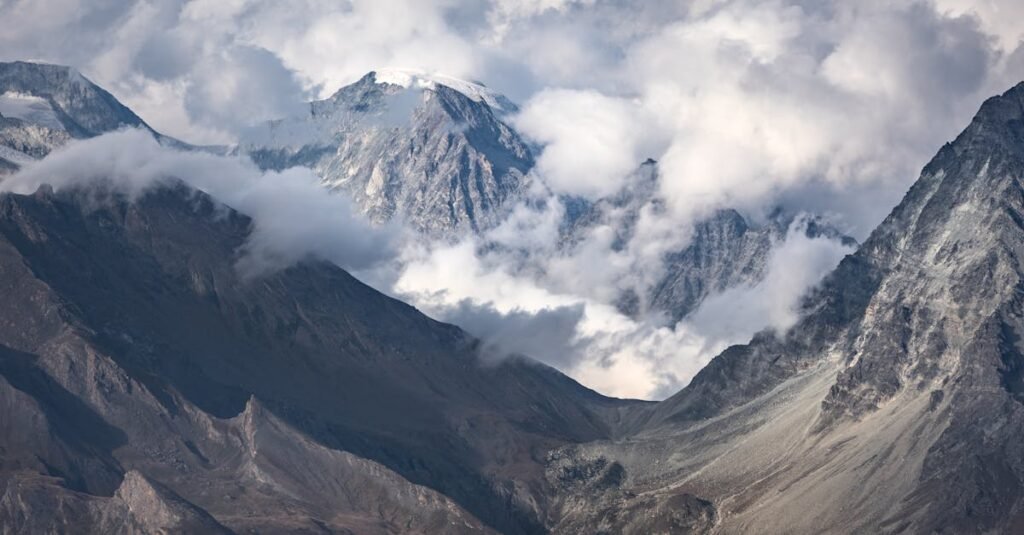 Stunning aerial view of the majestic Alps mountains in Aosta, Italy, surrounded by clouds.