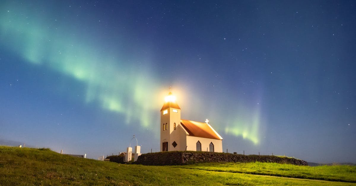 A stunning view of the Northern Lights illuminating a church in Iceland under a clear night sky.