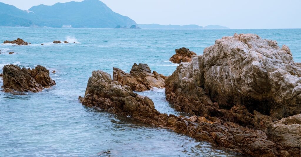 Tranquil ocean waves crash against rocky outcrops on a serene coastline, ideal for nature and travel themes.