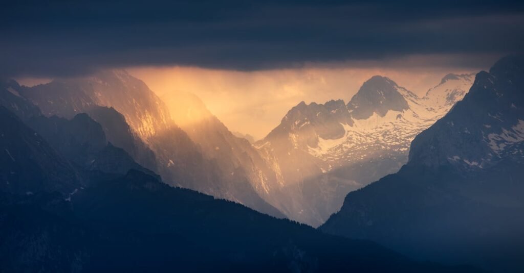 Sunset illuminates the majestic Alpine mountains under dramatic skies.