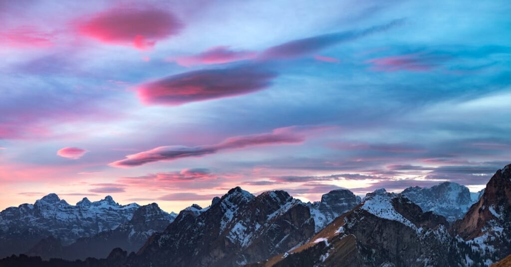 Captivating sunset over the snow-covered peaks of the Dolomites, with vivid pink and blue skies.
