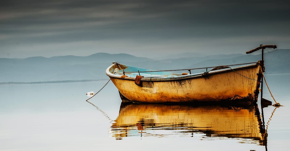 A tranquil morning scene of a fishing boat reflecting on calm waters with a cloudy sky in Manisa, Türkiye.