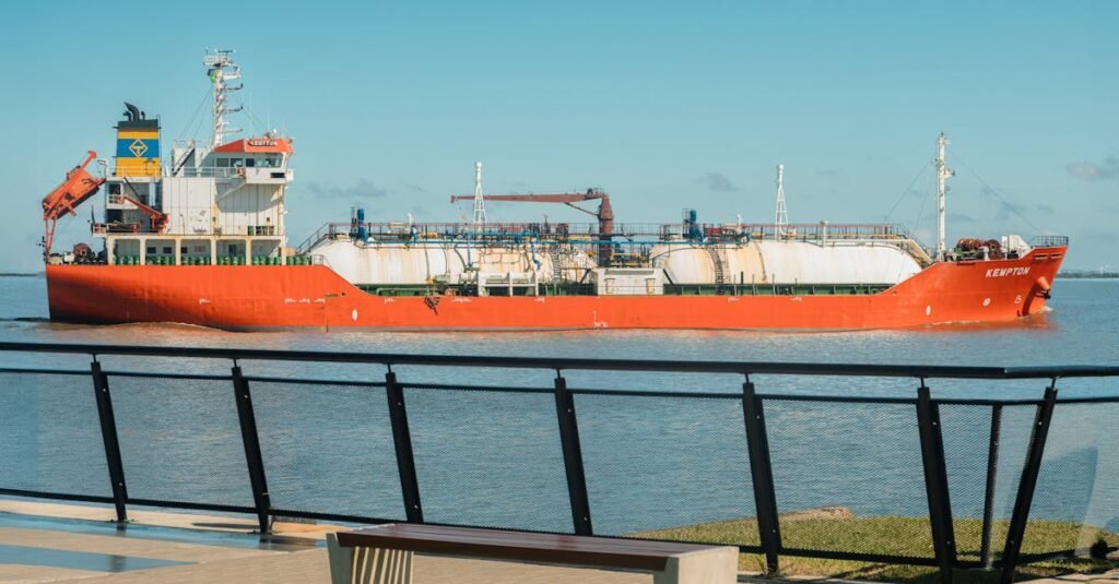 A red cargo ship passes through the harbor in Porto Alegre under a clear blue sky.