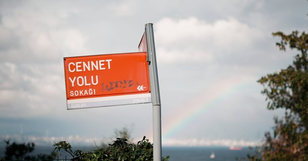 A vibrant rainbow arches over the Cennet Yolu Sokak street sign with lush greenery.