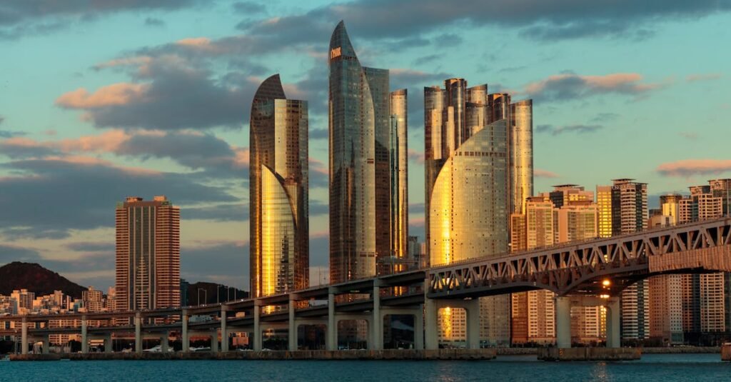 A stunning sunset view of the Busan skyline with bridge and skyscrapers reflecting sunlight.