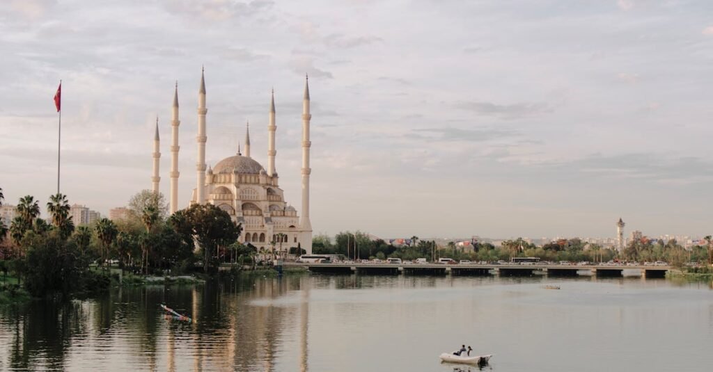 Scenic view of Sabancı Mosque and Seyhan River in Adana, Türkiye, featuring serene water reflection.